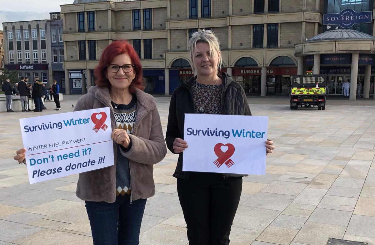 Two white women holding Surviving winter posters