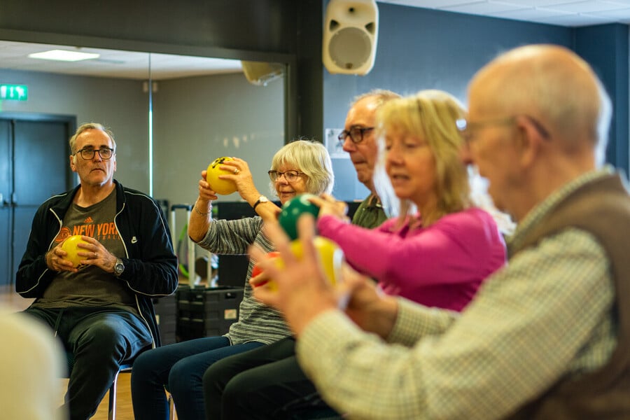 Older people doing chair exercises in a community hall